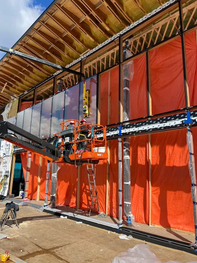 A large building is being built and windows are being installed.