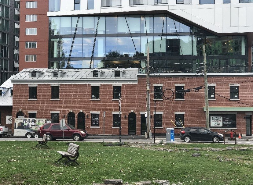 A brick building with a lot of windows is next to a large building with a lot of windows.