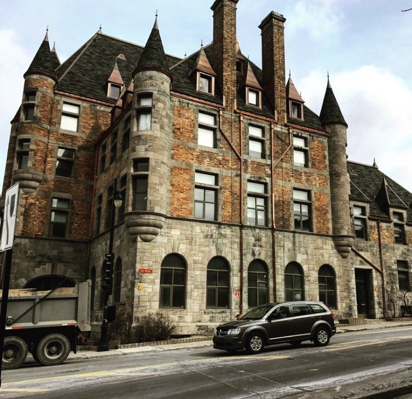 A car is parked in front of a large brick building