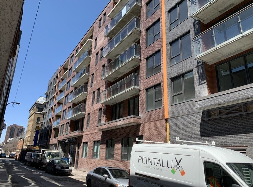 A white van is parked in front of a large apartment building.