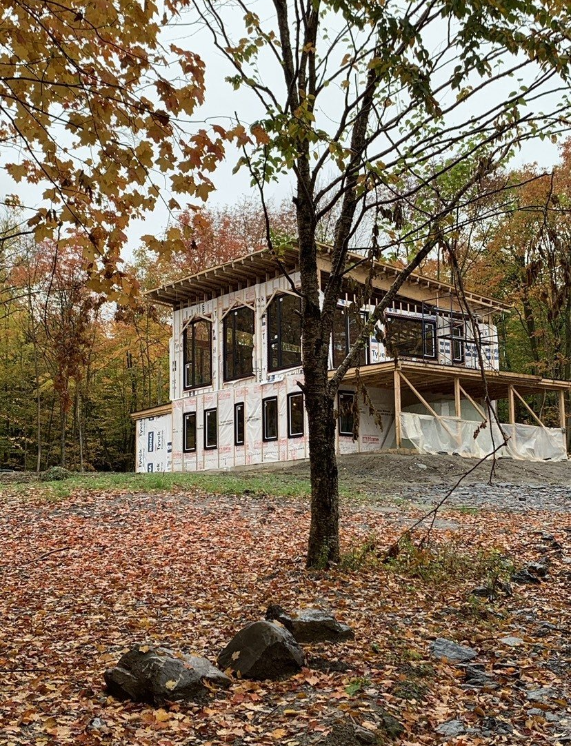 A house is being built in the woods with a lot of leaves on the ground.