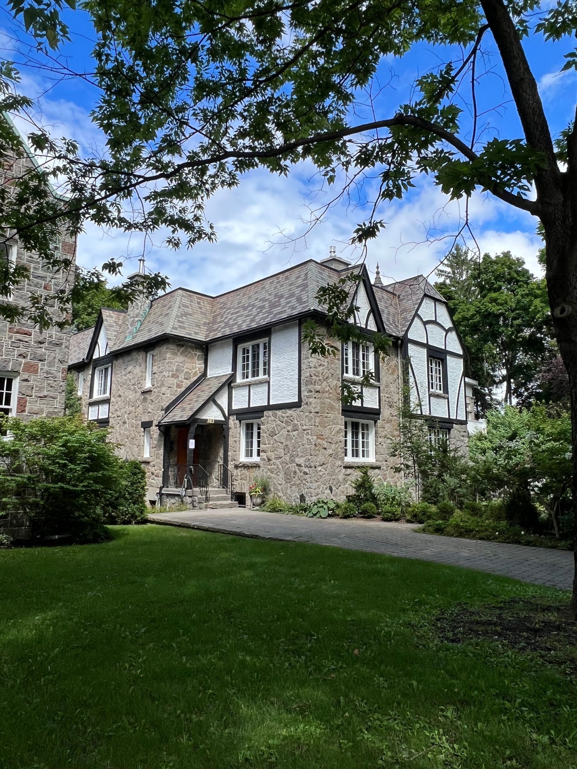 A large house is surrounded by trees and grass on a sunny day