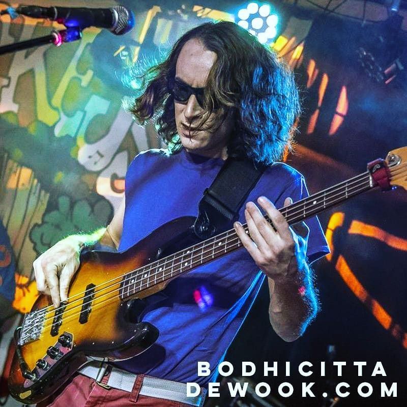 A man in a blue shirt is playing a bass guitar