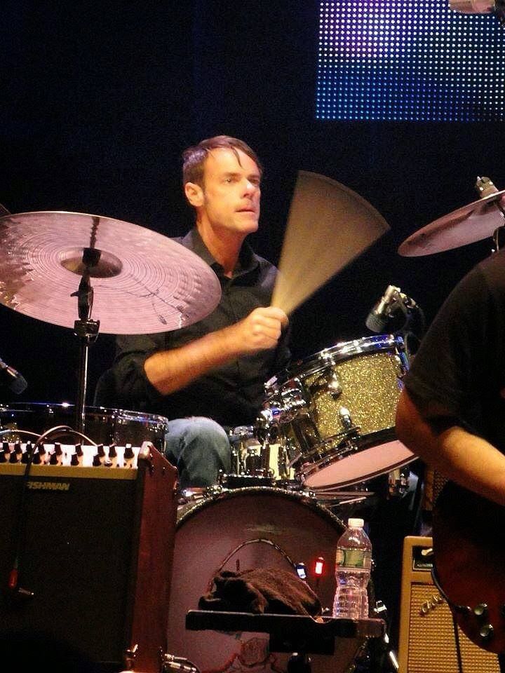 A man playing drums in front of a large screen