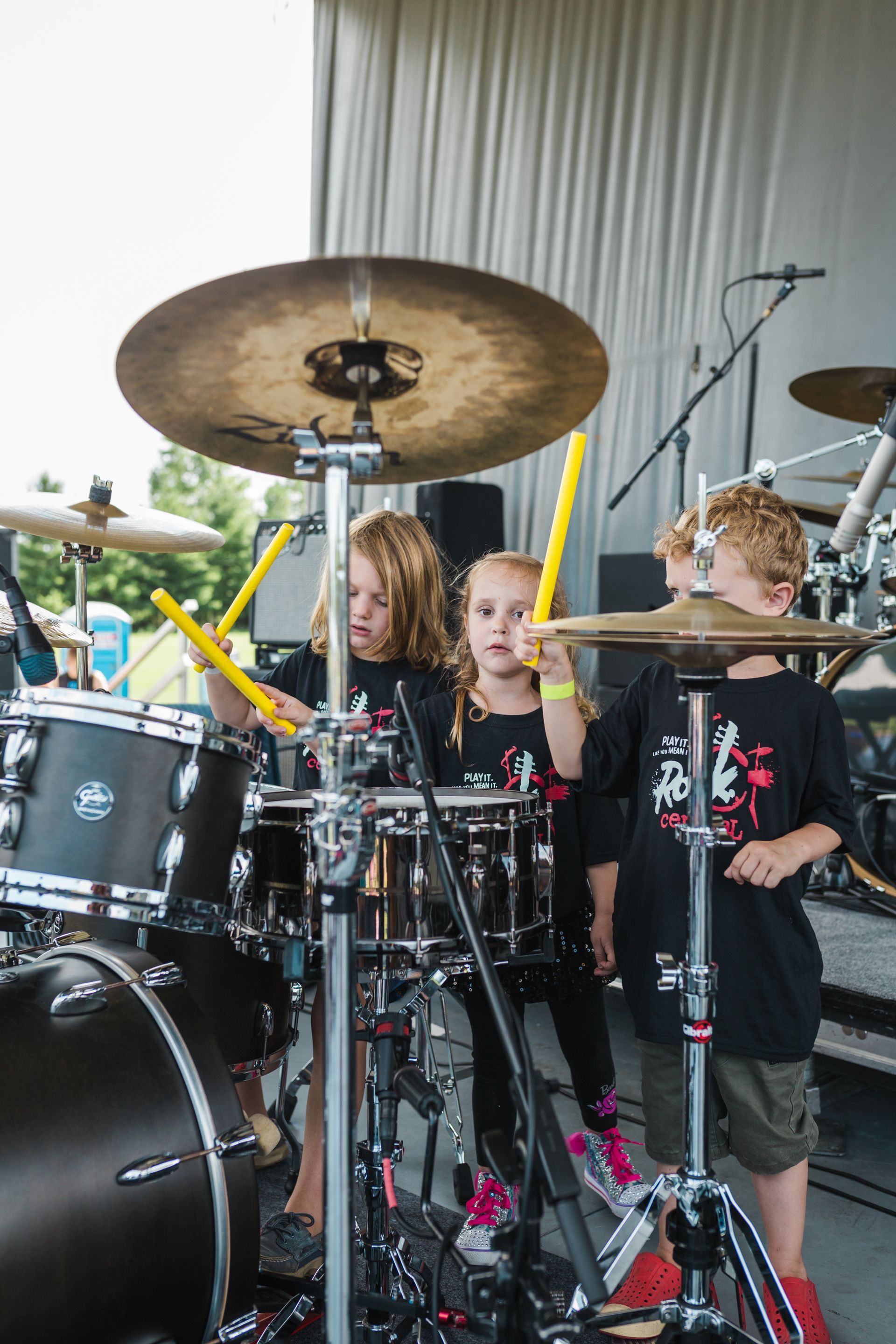 A group of young children are playing drums on a stage.