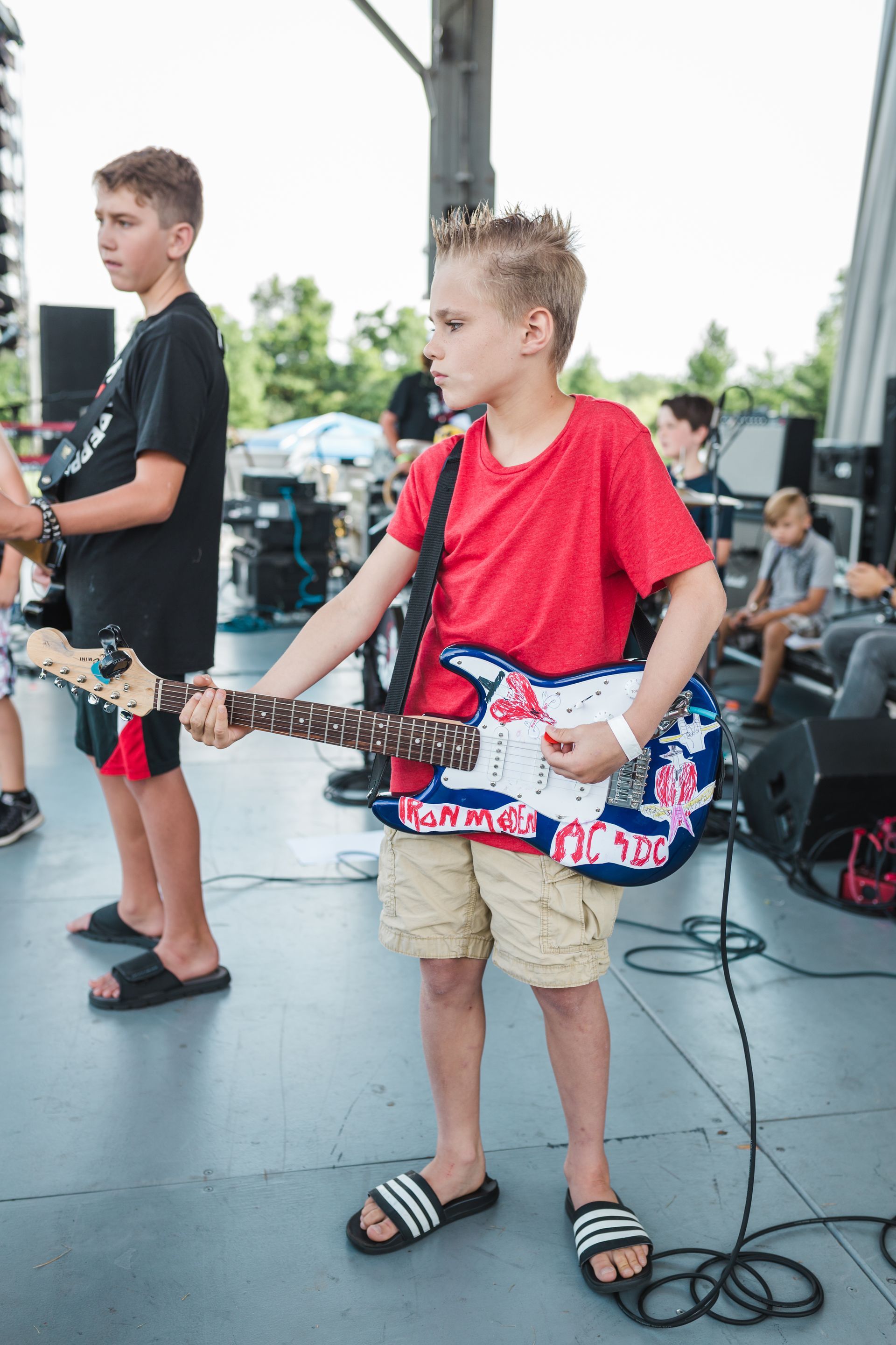 A young boy is playing a guitar on a stage.