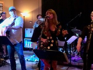 A woman is singing into a microphone in front of a band.