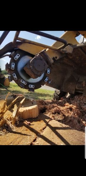 Close-up of a muddy excavator wheel and suspension beneath a raised machine on a dirt worksite