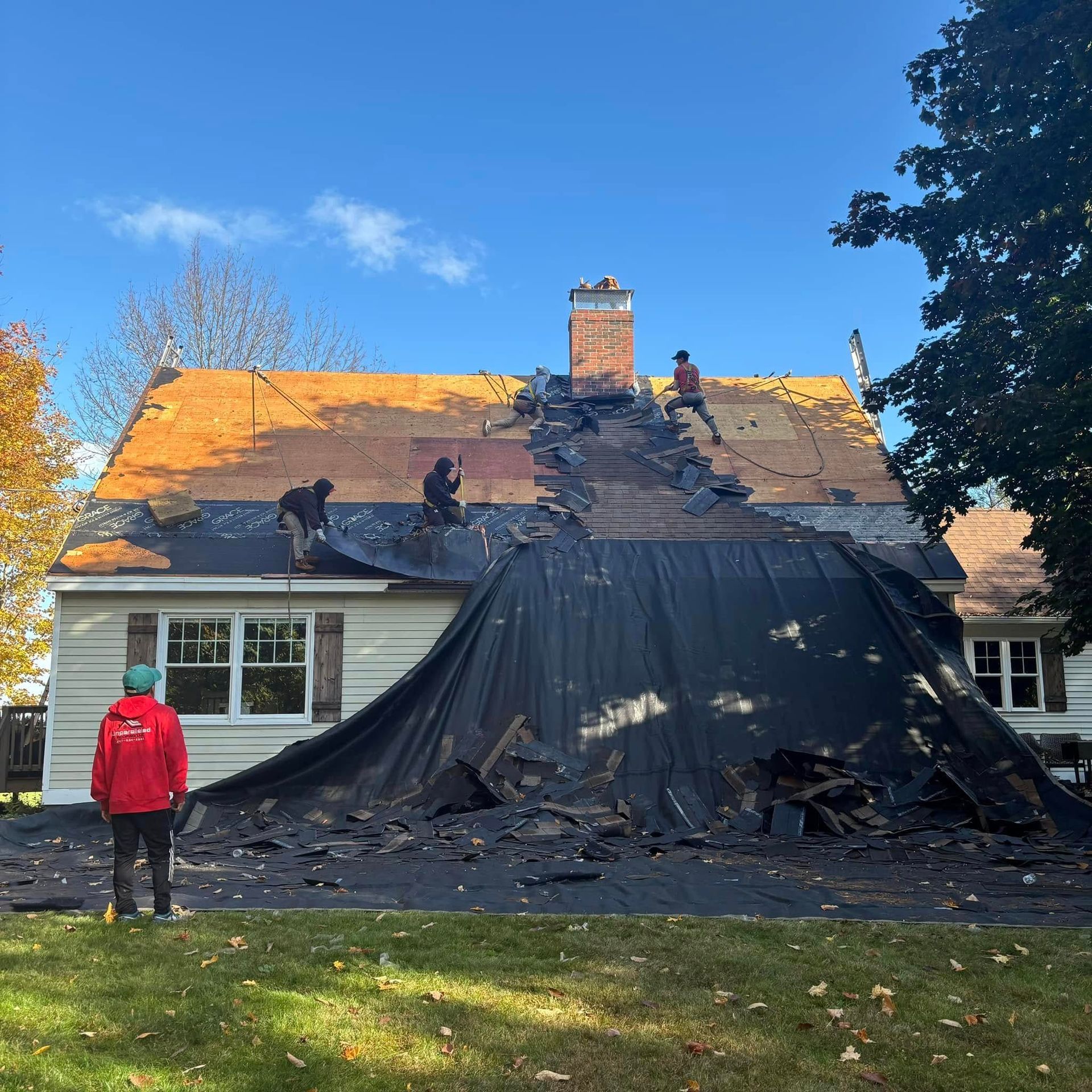 A man in a red jacket is standing in front of a house that is being remodeled