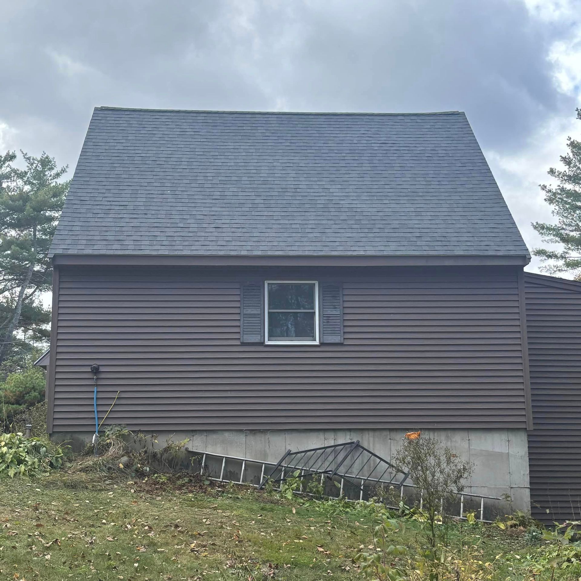 A brown house with a slate roof and a window