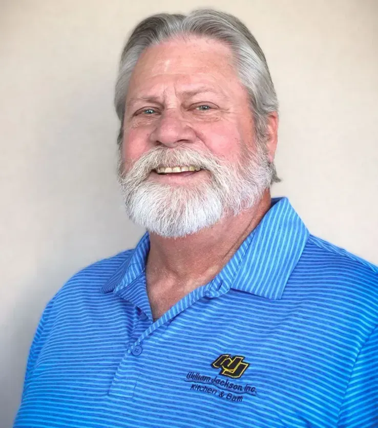 Smiling bearded man in a blue polo shirt against a plain background