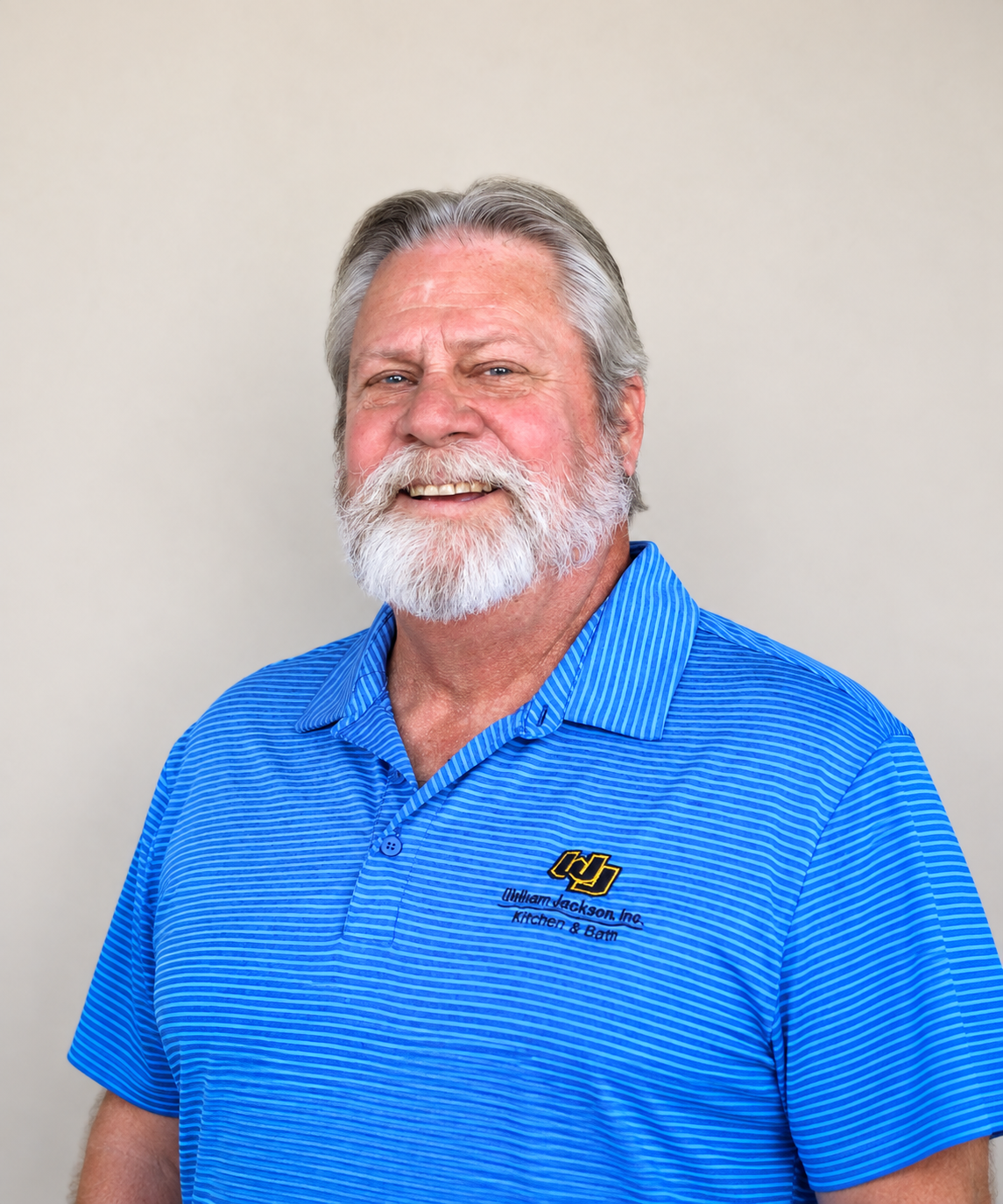 Smiling bearded man in a blue polo shirt against a plain background