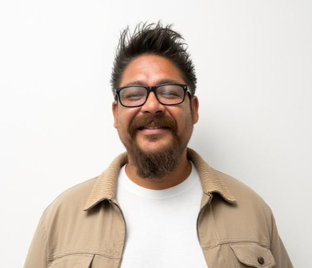Smiling person in glasses and a blue shirt against a plain white background
