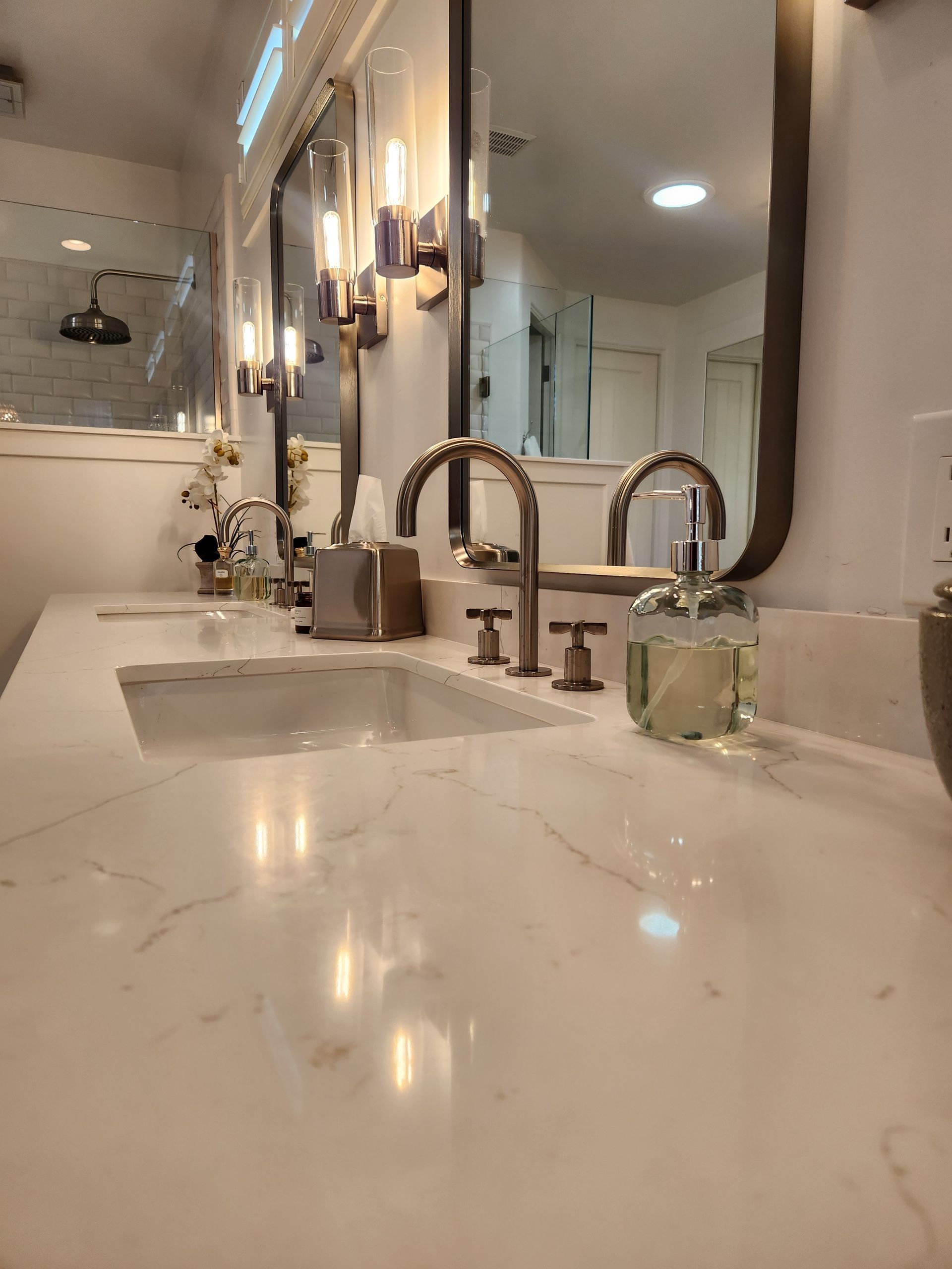 Modern bathroom vanity with marble countertop, double sinks, chrome faucets, and mirror lighting