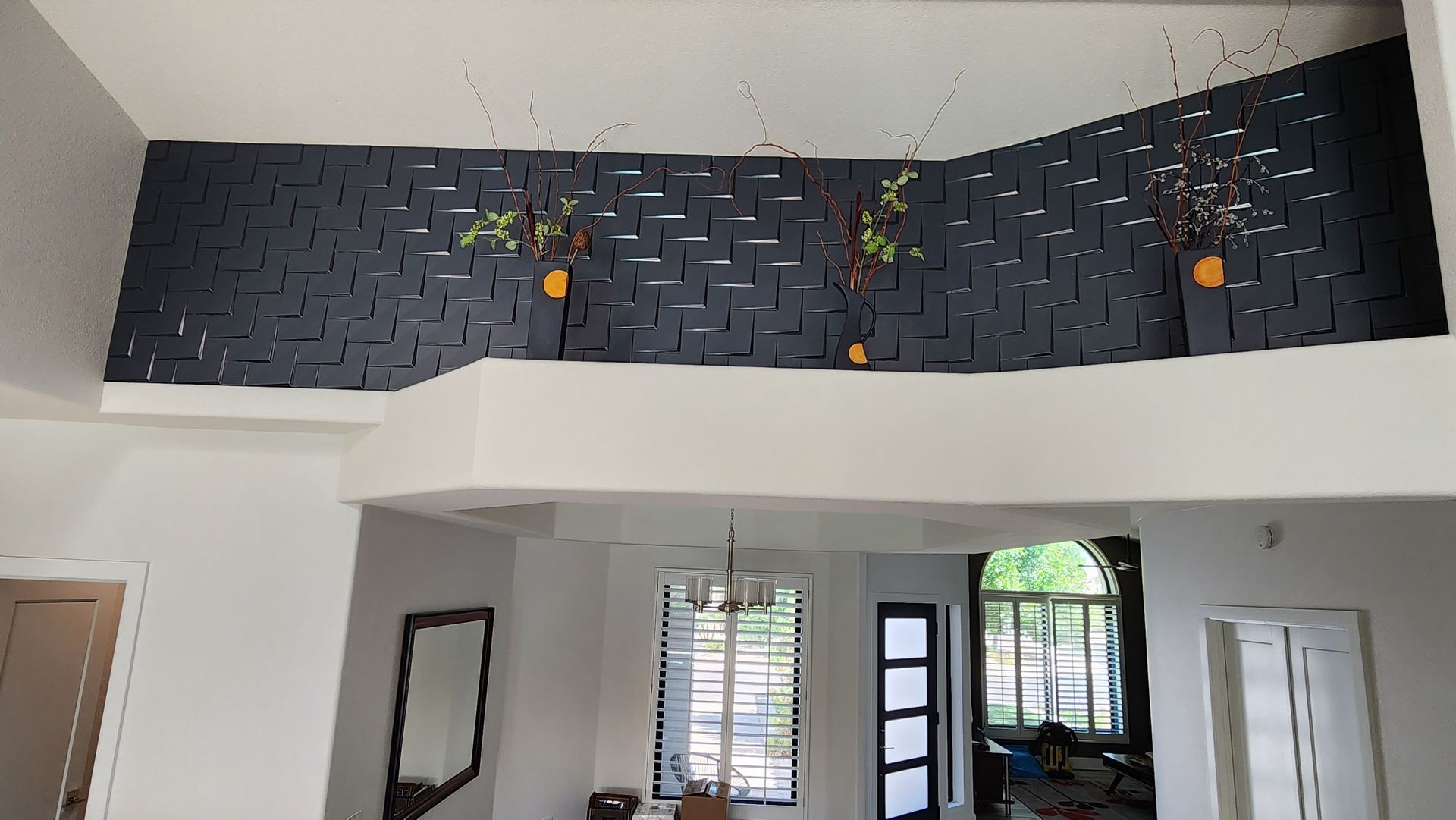 Modern room with high black brick accent wall, white walls, doors, and tall windows bringing in daylight