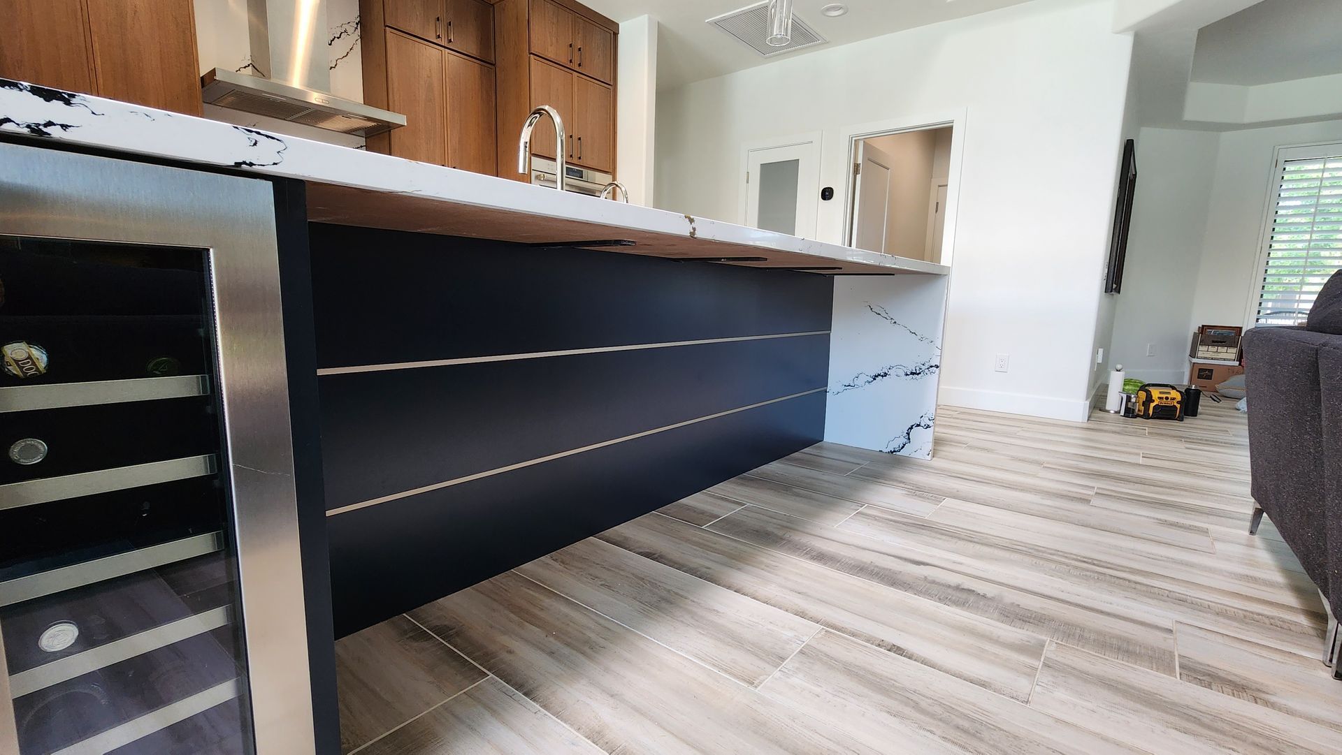 Modern kitchen with dark island cabinets, light wood floor, and white walls.