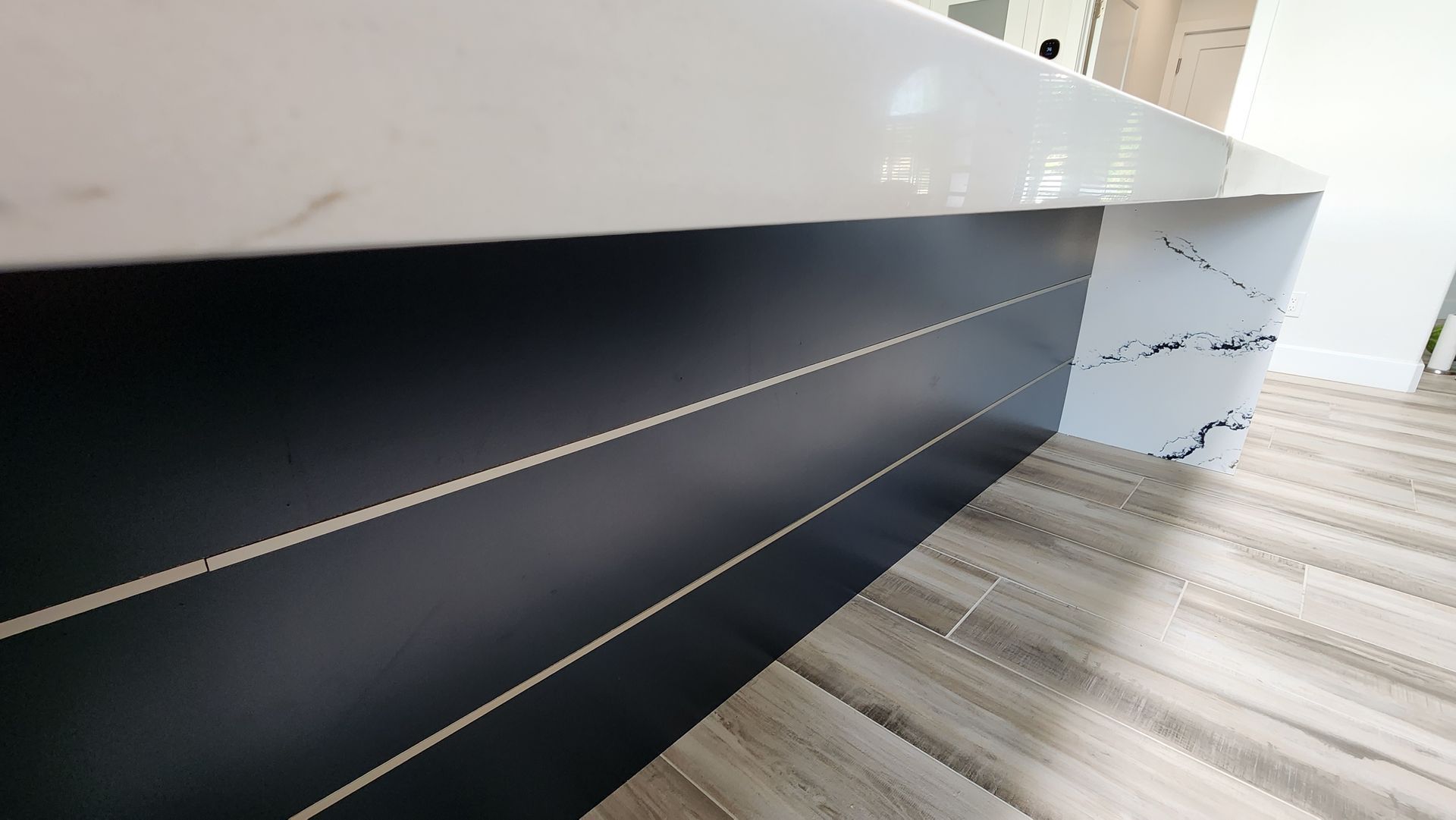Modern staircase with white and dark steps beside a glossy white wall.