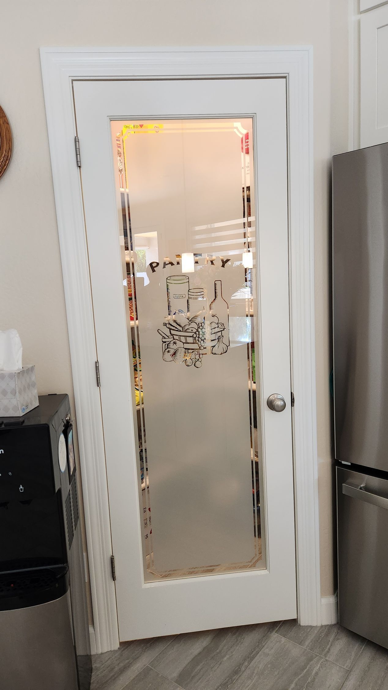 White door with a frosted glass panel and ornate design in a kitchen or hallway.