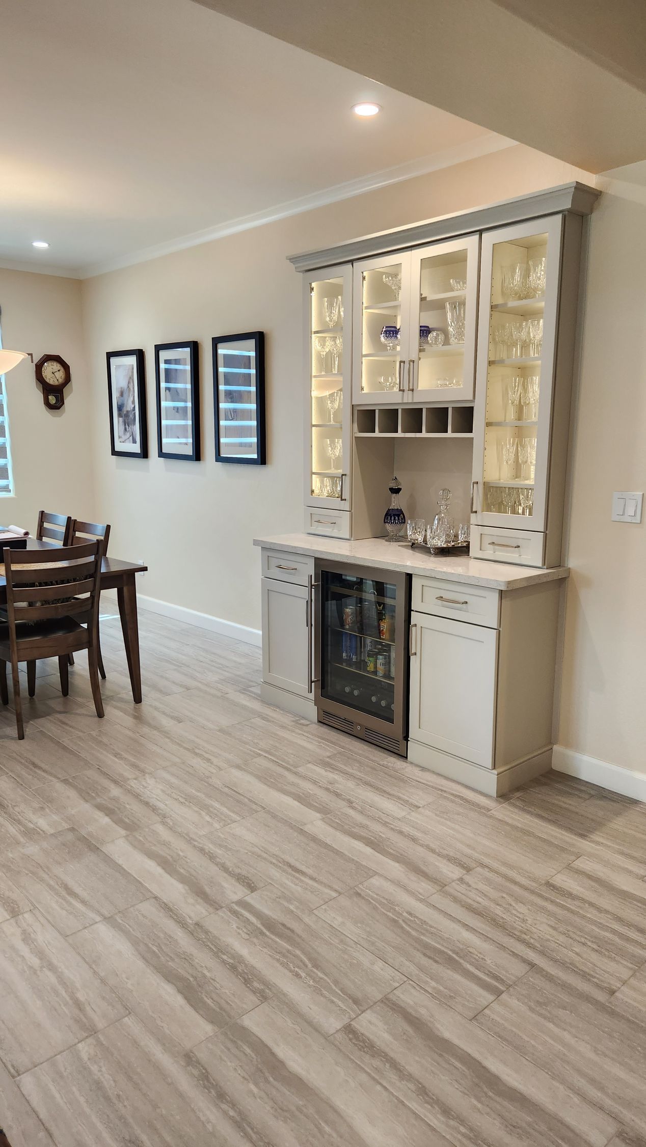 Spacious dining room with light wood floors, a built-in white cabinet, and framed wall art.