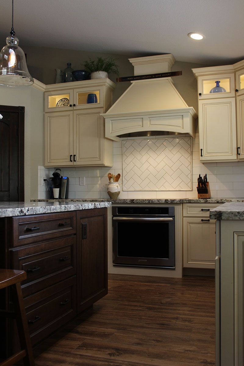 Modern kitchen with white cabinets, tile backsplash, stainless oven, and wood flooring