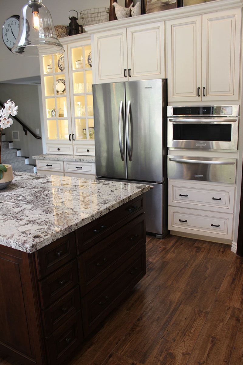 Modern kitchen with white cabinets, stainless steel fridge, built-in oven, and granite island countertop