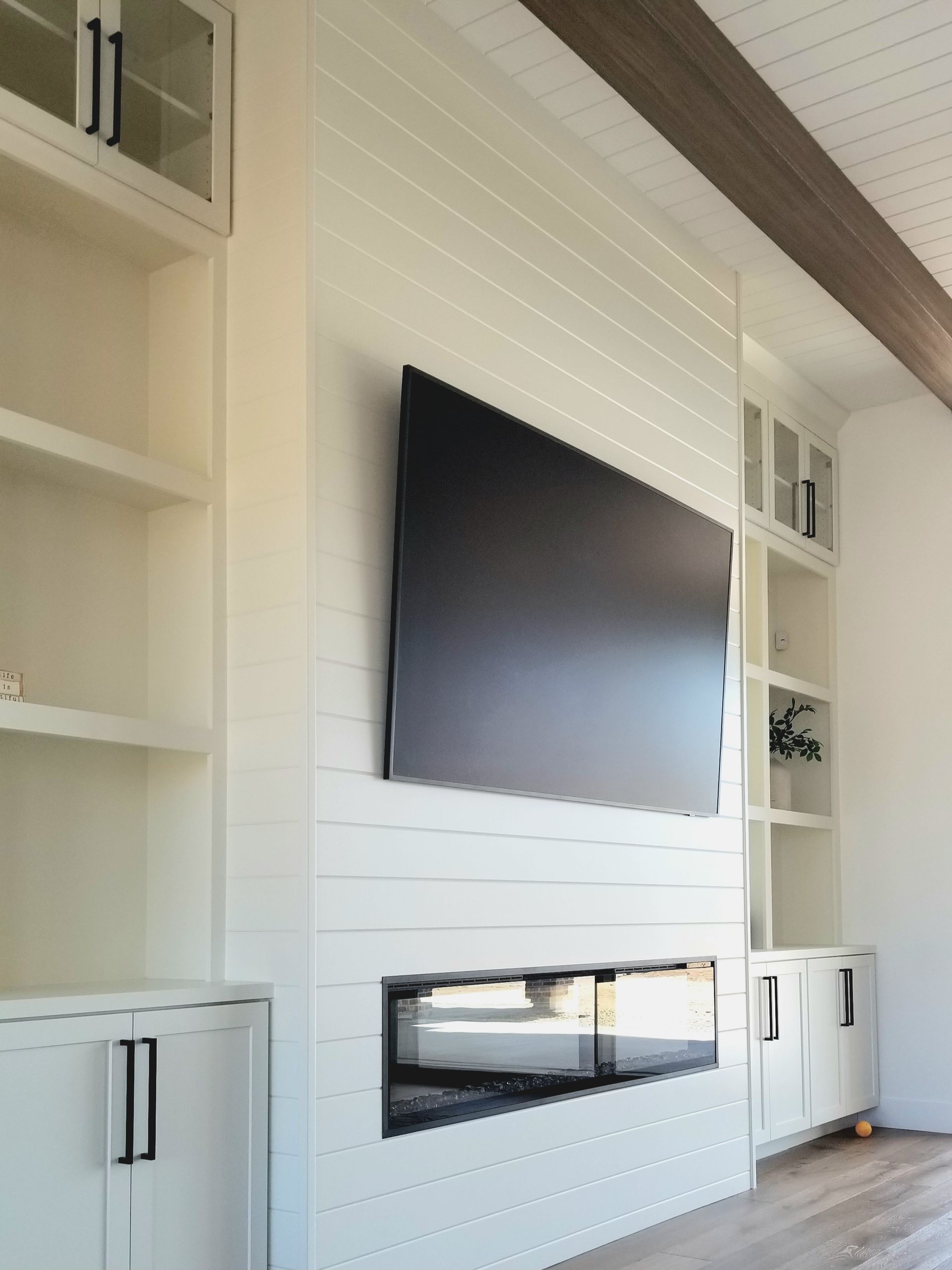 Modern living room with a wall-mounted TV above a white fireplace and built-in shelves