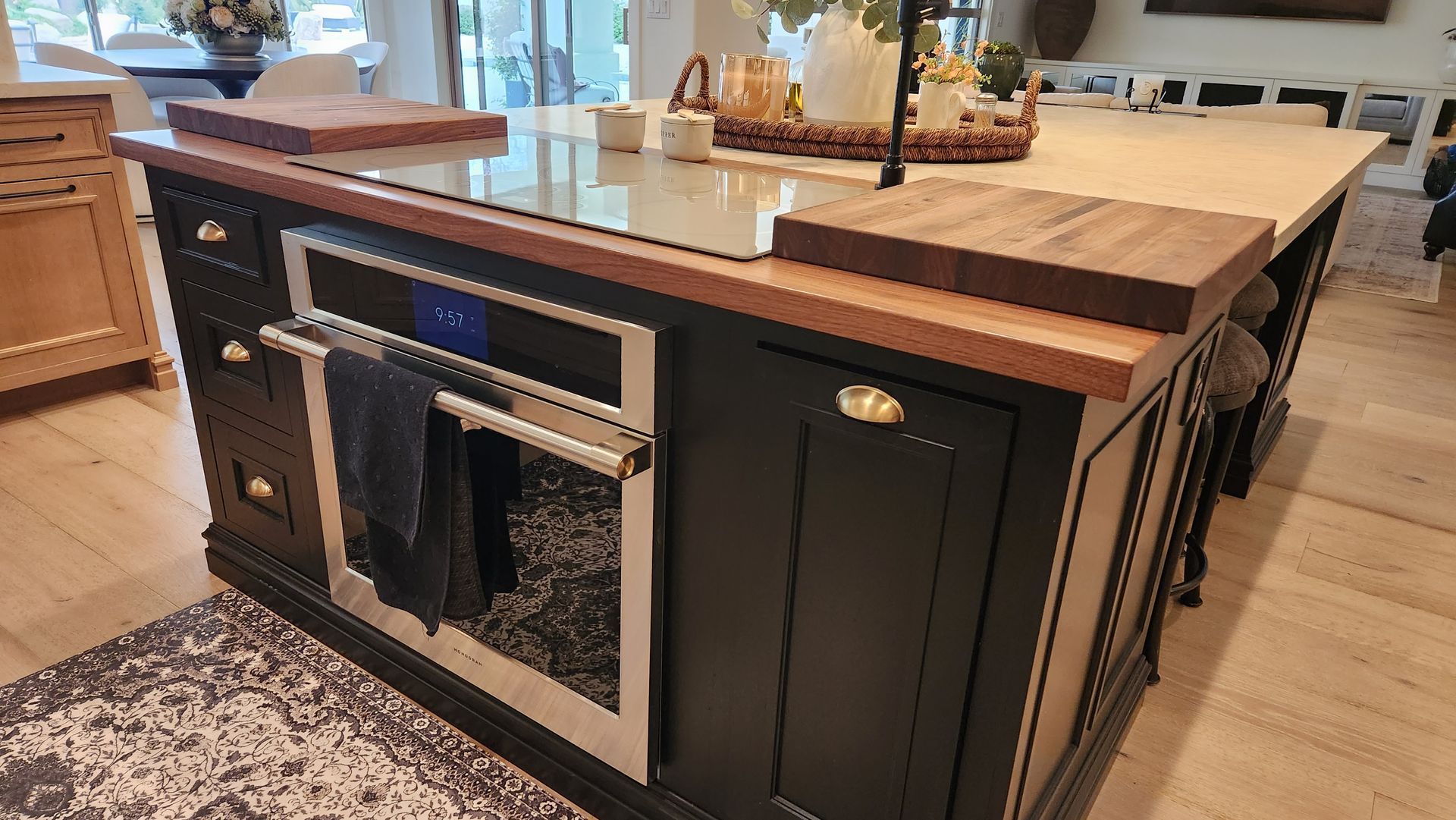 Kitchen island with built-in stove, black cabinets, and a wooden countertop in a modern kitchen