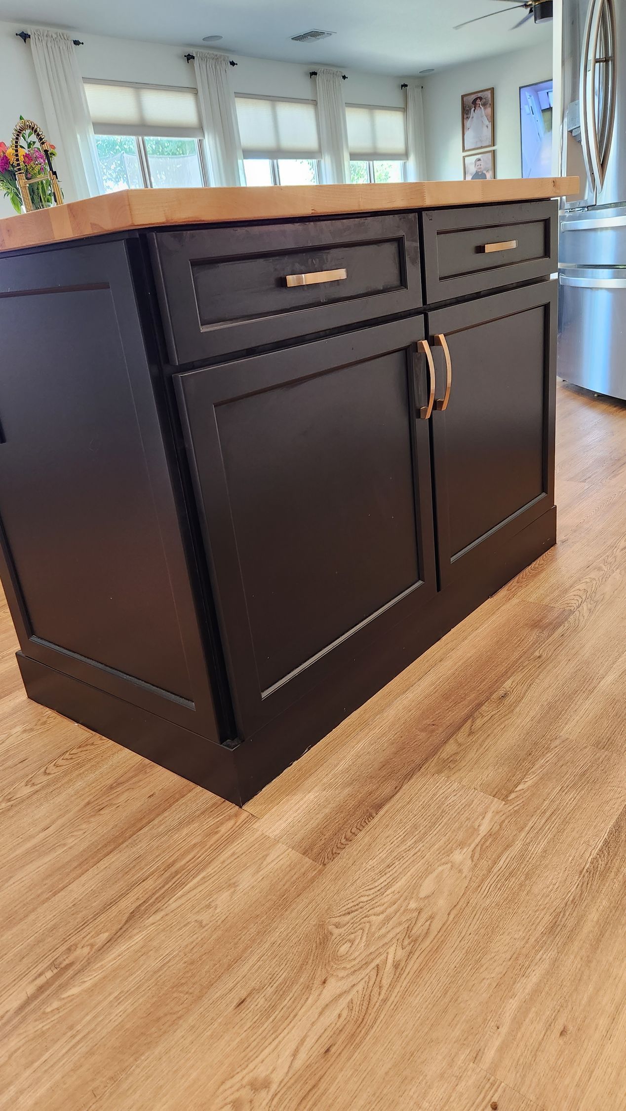 Black kitchen island with drawers and cabinets on a wood floor in a bright home interior