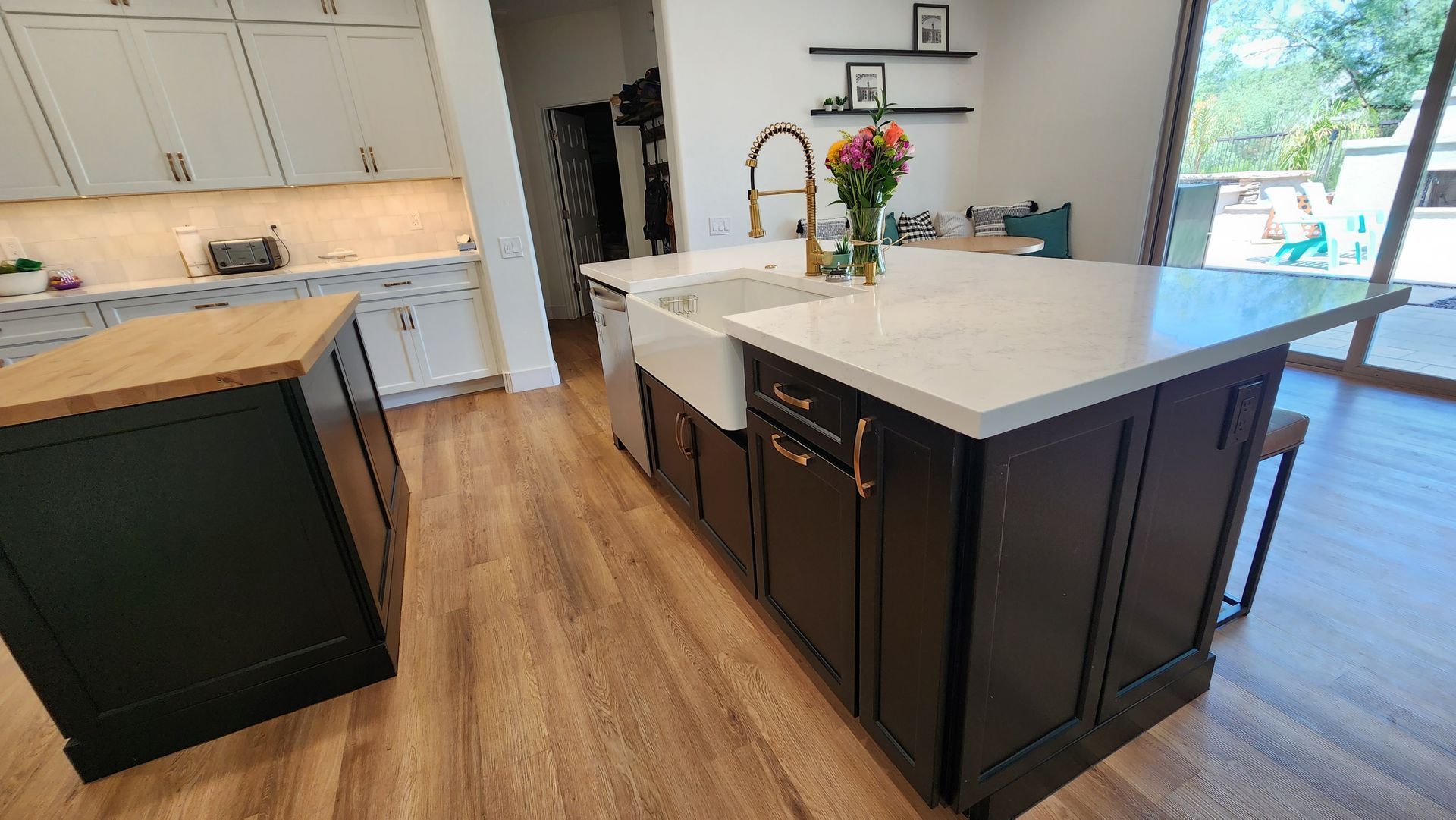 Modern kitchen with dark island cabinets, white countertops, wood floors, and large sliding glass doors.