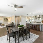 Open-concept living and dining room with kitchen island, hardwood floors, and neutral decor