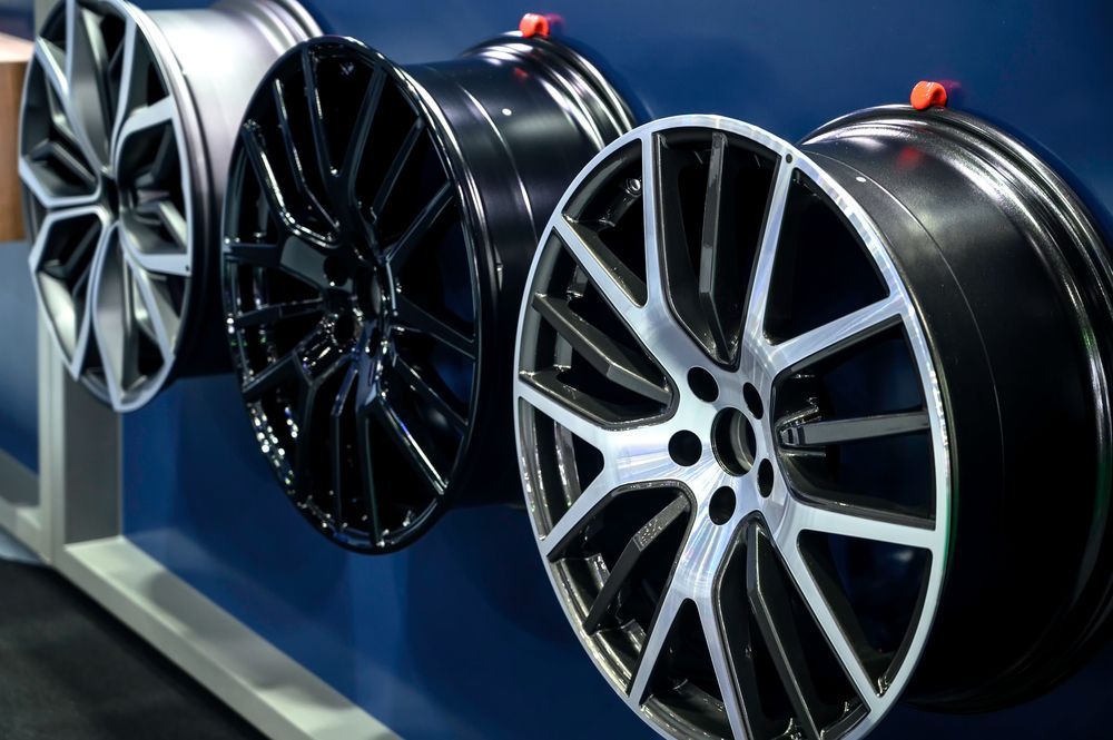 Four Shiny Car Rims Displayed on a Blue Wall — Ben's Tyres in Narromine, NSW