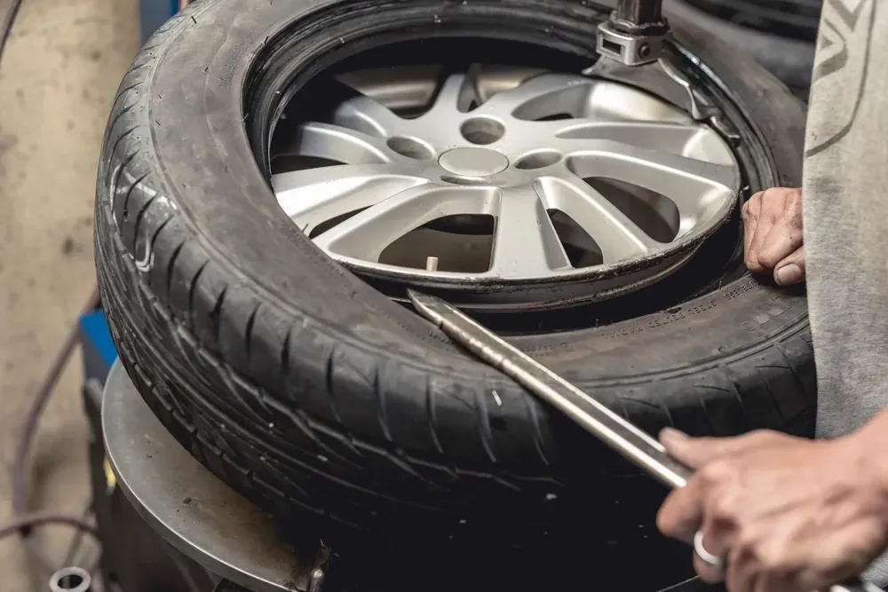 Person using a tire machine to remove a tire from a silver rim. — Ben's Tyres in Narromine, NSW