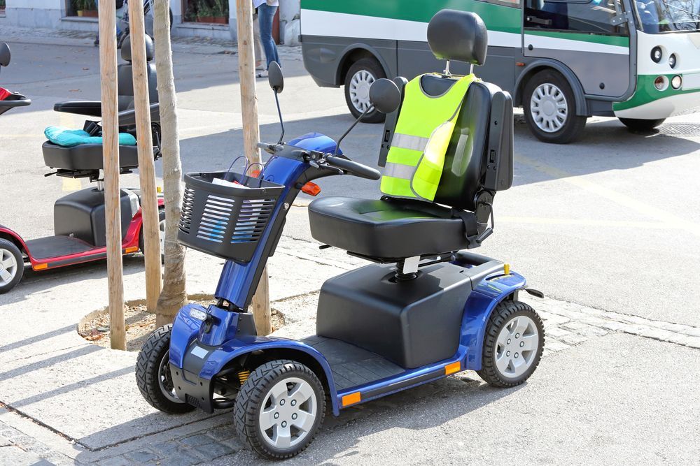Blue Mobility Scooter With a Yellow Vest, Parked on Pavement — Ben's Tyres in Wellington, NSW