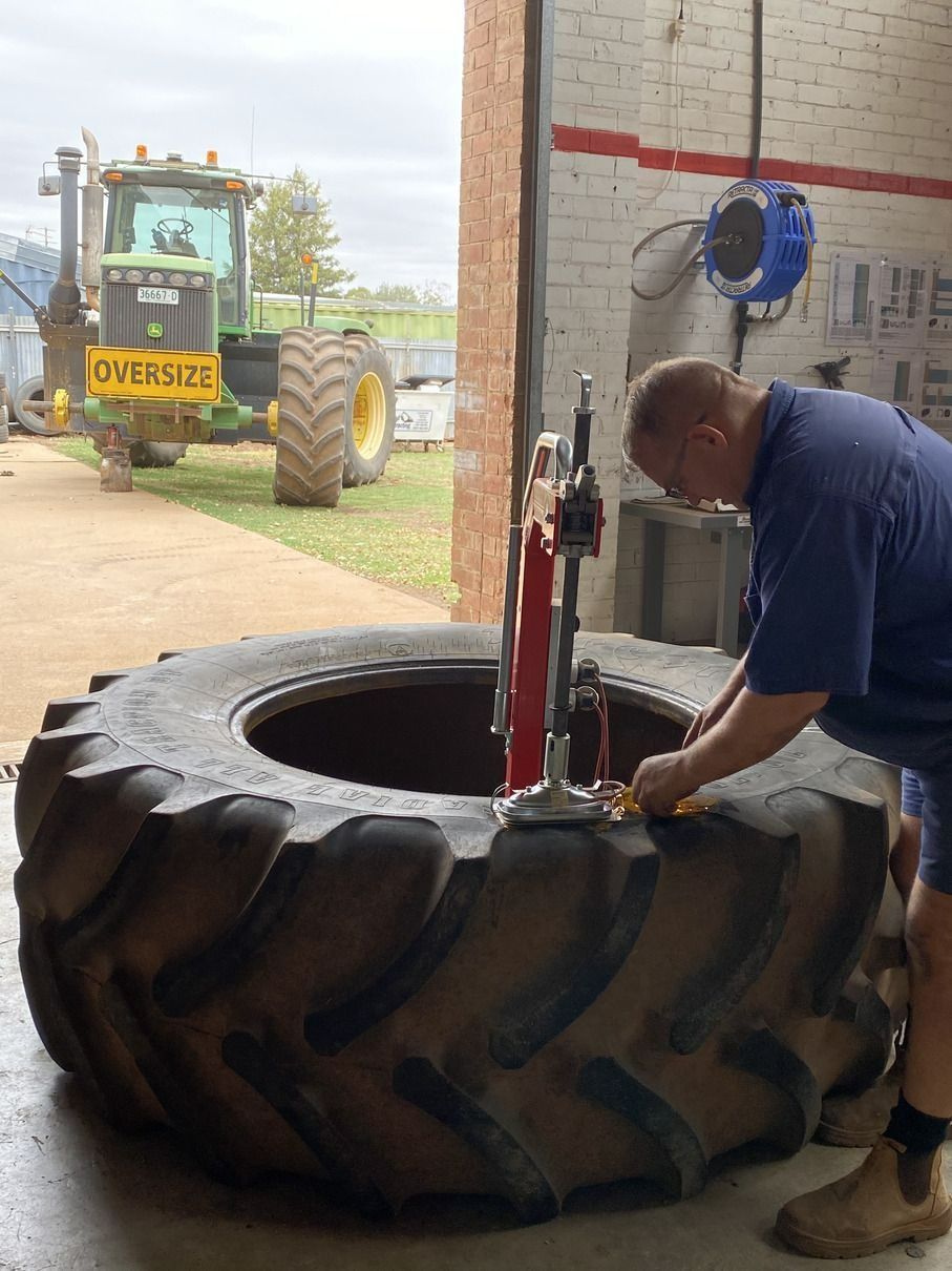 Man Repairing a Large Tractor Tire Inside a Garage — Ben's Tyres in Wellington, NSW