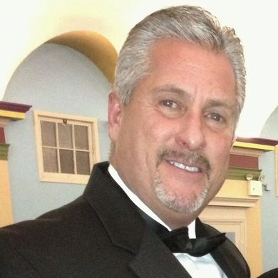 A man in a tuxedo and bow tie smiles for the camera