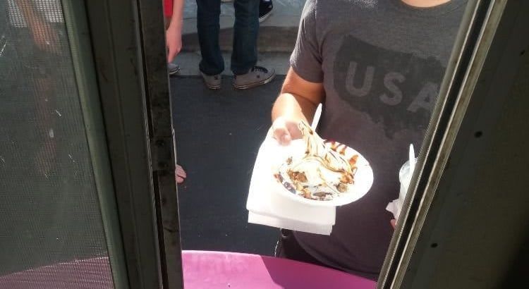 Person holding a plate of food at a doorway, wearing a dark USA shirt.