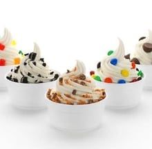 Three cups of swirled ice cream topped with colorful candy pieces and chocolate chips
