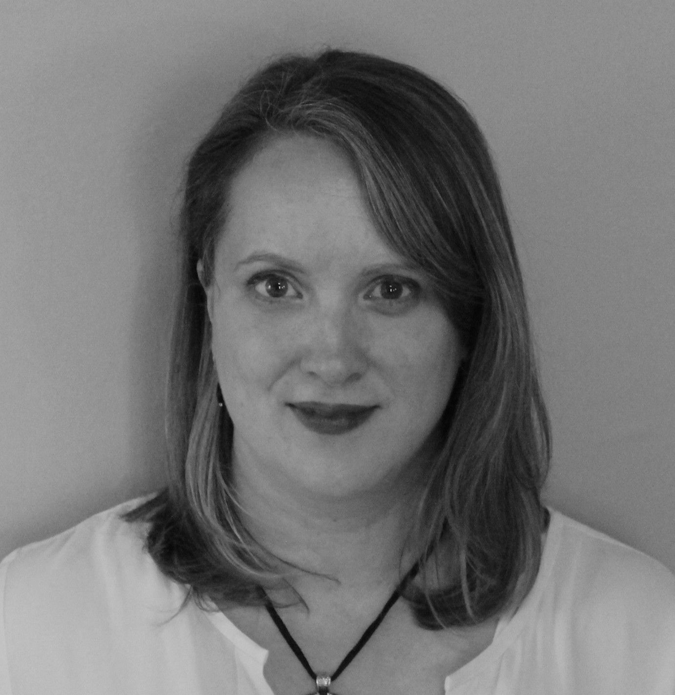 Black-and-white headshot of a woman with shoulder-length hair, wearing a white blouse and necklace.