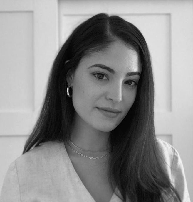 Black-and-white portrait of a woman with long dark hair, wearing a light top and small hoop earrings, smiling softly