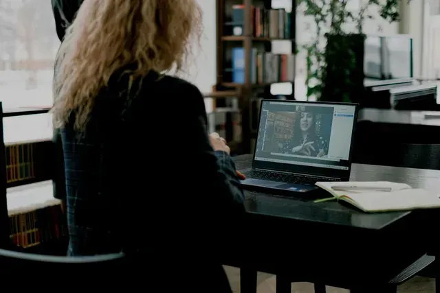 Person working at a desk with a laptop in a library, seen from behind