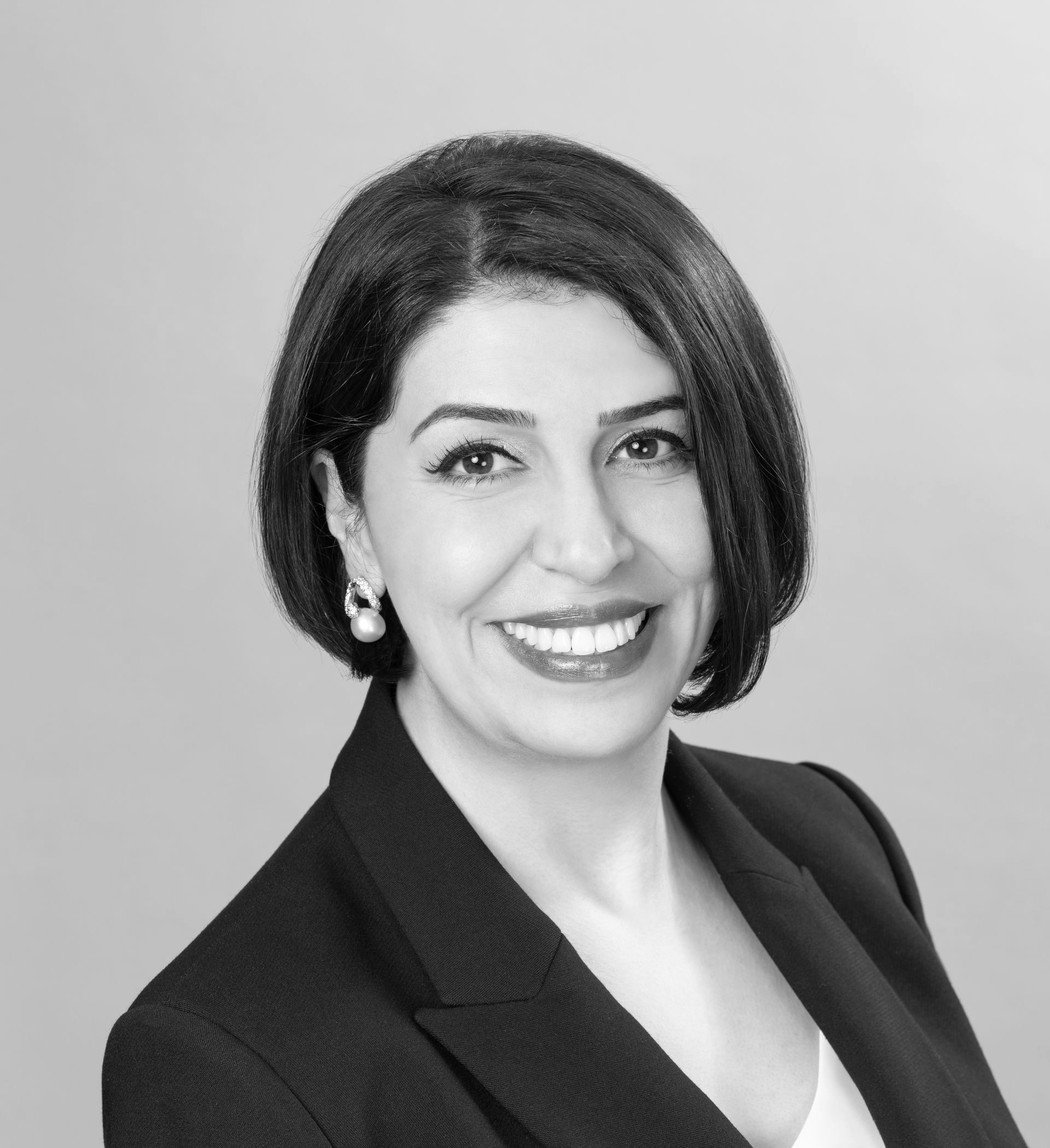 Smiling woman in a dark blazer against a light gray background
