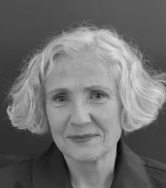 Black-and-white portrait of a person with short wavy hair, facing forward with a slight smile.