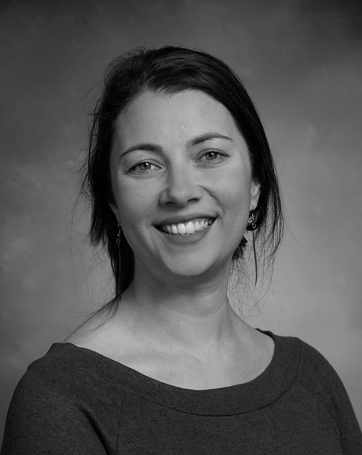 Smiling woman in a dark top against a plain studio backdrop
