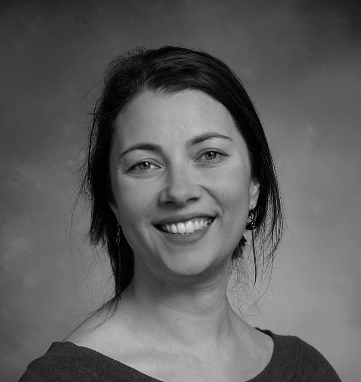 Smiling woman in a dark top against a plain gray background