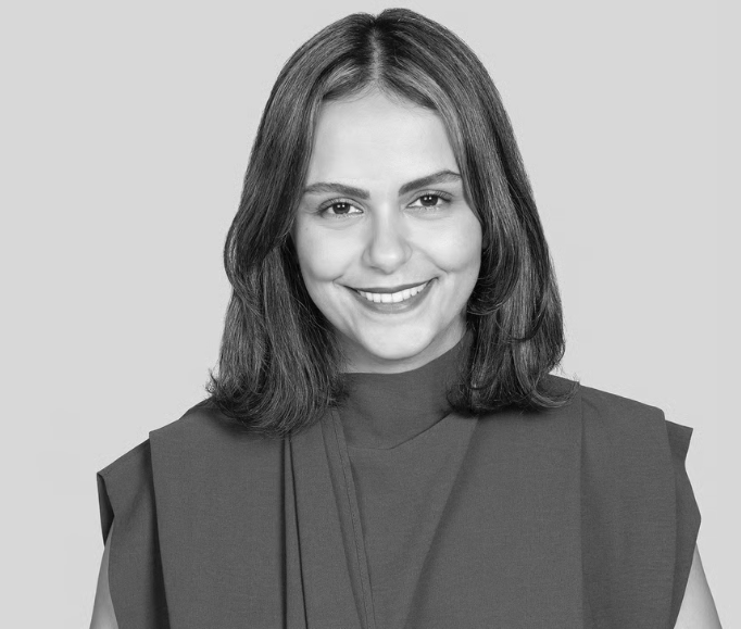 Smiling person in a dark top, facing forward against a plain light background