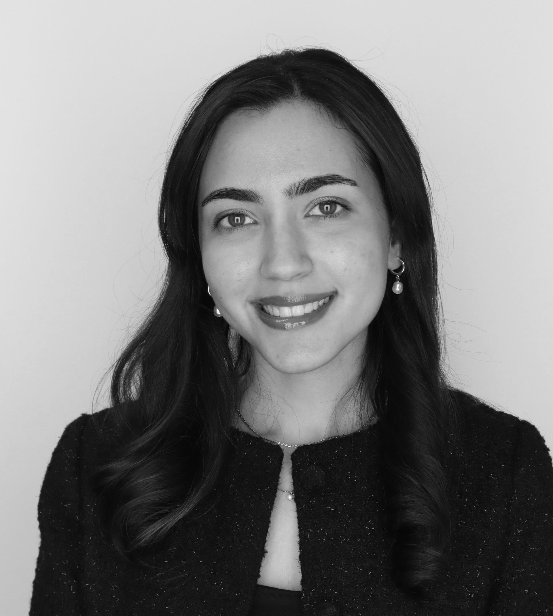 Portrait of a smiling woman with long dark hair in a dark jacket against a light background