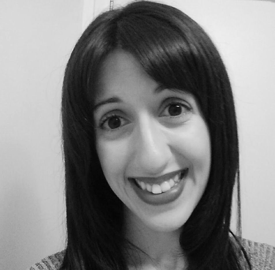 Close-up black-and-white portrait of a smiling person with straight dark hair and bangs