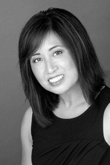 Portrait of a smiling woman with shoulder-length dark hair against a gray background