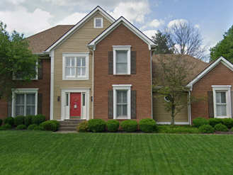 Two-story house with brown brick and tan siding, red front door, green lawn. Two-story house with brown brick and tan siding, red front door, green lawn.