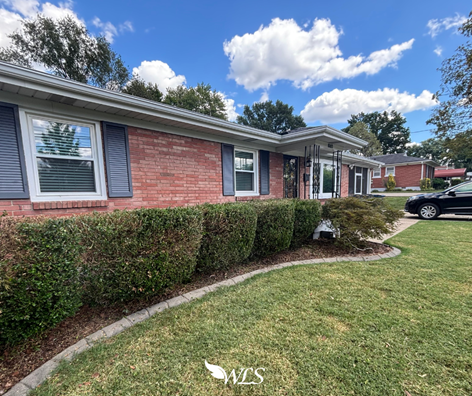 Brick house with neatly trimmed bushes and green lawn under a blue sky. Brick house with neatly trimmed bushes and green lawn under a blue sky.